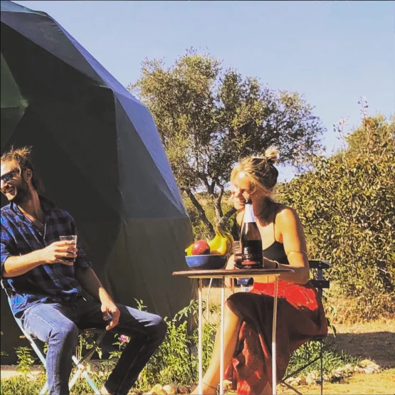 Couple enjoying breakfast outdoors next to their army green geodesic dome